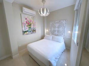 a small bedroom with a white bed and a chandelier at Apartamento Arquillo de la Plata in Seville