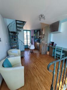 a living room with a white couch and a spiral staircase at Gîte Milly - 2 studios en coeur de ville in Milly-la-Forêt