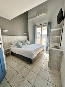 a bedroom with a bed and a large window at Hotel Les Palmiers En Camargue in Saintes-Maries-de-la-Mer