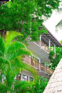 a white building with a balcony and trees at Turtle Paradise in Tangalle