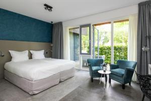 una camera d'albergo con un letto e due sedie di Hotel De Roode Schuur a Nijkerk