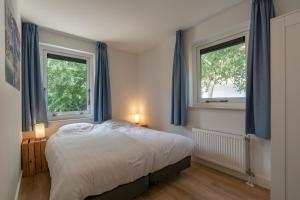 a bedroom with a bed and two windows at Villa Duynopgangh 16 Julianadorp aan Zee in Julianadorp