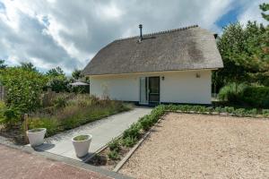 una pequeña casa blanca con techo de paja en Villa Duynopgangh 16 Julianadorp aan Zee en Julianadorp