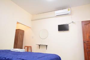 1 dormitorio con 1 cama azul y TV en โคบาล ห้องพักรายวัน, en Chom Thong