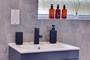 a bathroom sink with two bottles of alcohol on it at #Upmarket, Exceptional 4 bed house, with free parking, close to KFc McDonald ALDI and centre in Sheffield