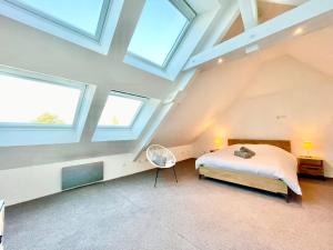 a attic bedroom with a bed and two windows at Charmante maison - centre-ville Colmar in Colmar