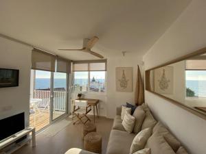 een woonkamer met een bank en een televisie bij Montaber Apartments - Sant Pol de Mar in San Pol de Mar