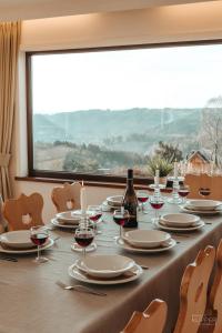 einem langen Tisch mit Gläsern Wein und einem Fenster in der Unterkunft L'Aurore des Hautes Fagnes 30 pers- Malmedy, vue exceptionnelle, wellness in Malmedy