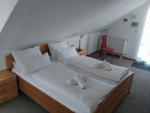 ノイシュタット・アン・デア・ヴァインシュトラーセにあるGästehaus Helbighofのベッドルーム1室(白いシーツと赤い椅子が備わるベッド2台付)