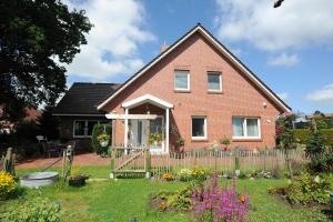 a red brick house with a fence in the yard at Ferienwohnung Zum Königsmoor 65336 in Moormerland