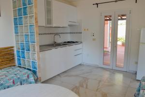 a kitchen with white cabinets and a sink at Onda Su Onda Appartamenti in Seccheto