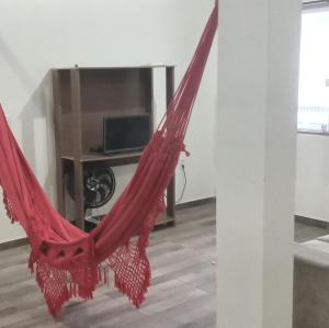 hamaca roja en una habitación con TV en Casa 3 quartos próxima as praias até 8 hóspedes., en Imbituba