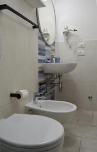 a bathroom with a sink and a toilet and a mirror at Onda Su Onda Appartamenti in Seccheto