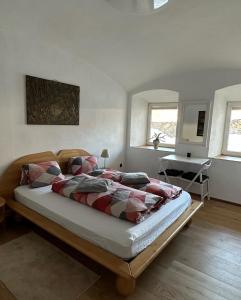 Lambichl的住宿－Wood Apartement，一间卧室配有一张床、一张桌子和两个窗户