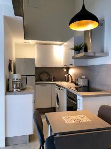 a kitchen with white cabinets and a table with chairs at T2 en duplex & terrasse in Saint-Priest