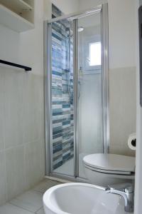 a bathroom with a shower and a toilet and a sink at Onda Su Onda Appartamenti in Seccheto +37 photos