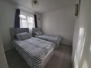 2 camas en una habitación pequeña con ventana en 2 Bedroom Flat near Heathrow airport en Yiewsley