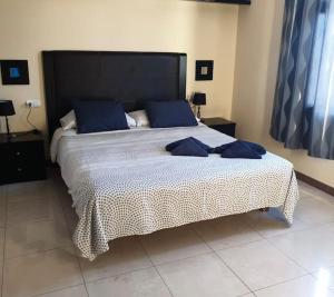 a bedroom with a large bed with blue pillows at Riviera Park 7A - Air con- Wi-Fi- UK channels- 5 minutes walking from the sea in Tías