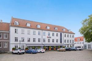 een groot wit gebouw met auto's geparkeerd op een parkeerplaats bij Best Western ToRVEhallerne in Vejle