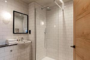 a white tiled bathroom with a sink and a shower at The Park Hotel in Teddington