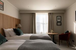 a hotel room with two beds and a window at The Park Hotel in Teddington