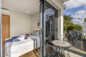 una camera da letto con un letto e un balcone con un tavolo di Casa da Praia, 2min de la PLAGE, hyper centre a Machico
