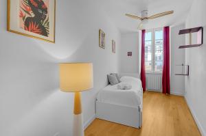 Cette chambre blanche comprend un lit et une lampe. dans l'établissement L'île aux Tounis - T3 Moderne centre de Toulouse, à Toulouse