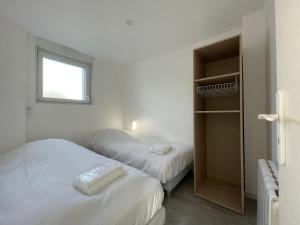 2 Betten in einem kleinen Zimmer mit Fenster in der Unterkunft Héolia - Maison à 250m de la plage Damgan in Damgan