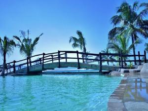 a bridge over a body of water with palm trees at Nghunghwa Lodge in Vila Praia Do Bilene