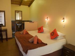 um quarto com uma cama com almofadas laranja em Nghunghwa Lodge em Vila Praia do Bilene