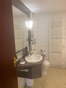a bathroom with a sink and a toilet and a mirror at Hotel Villa Sophia in Warendorf