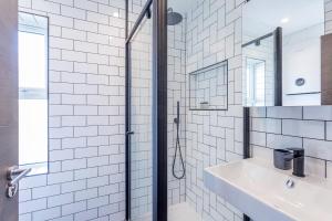a white tiled bathroom with a sink and a shower at The Stanley Maisonette in Teddington