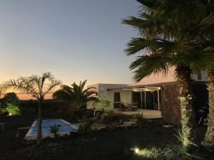 una casa con una palmera delante de ella en Majanicho Rock - villa with heated pool, en Lajares