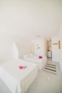 - une chambre blanche avec 2 lits blancs et des fleurs dans l'établissement Kontseta, à Mérikhas