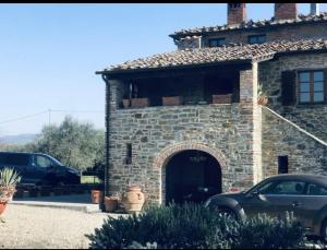 un bâtiment en pierre avec une voiture garée devant. dans l'établissement Casale di mamma Antonella, à Arezzo