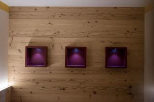 a wall with three televisions on a wooden wall at Hotel Crepei in Pozza di Fassa