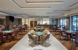 a restaurant with tables and chairs and windows at Vivanta Mangalore Oldport Road - Formerly Known as Taj Manjarun in Mangalore