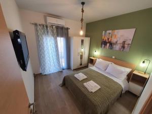a bedroom with a bed and a flat screen tv at La Casita a brand new apartment in the center in Argostoli
