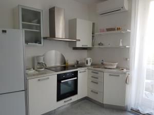 uma cozinha com armários brancos e um forno com placa de fogão em Charmant 2p proche mer et plage au calme em Menton