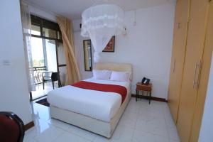 a bedroom with a large white bed and a window at Frontiers Hotel & Conference Entebbe in Entebbe