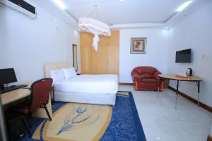 a hotel room with a bed and a desk and a chair at Frontiers Hotel & Conference Entebbe in Entebbe