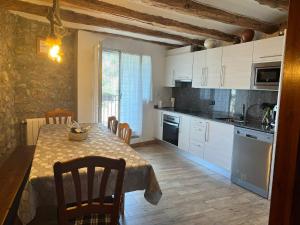 a kitchen with a table and a kitchen with white cabinets at Casa Corroncui in Sant Marti de Canals