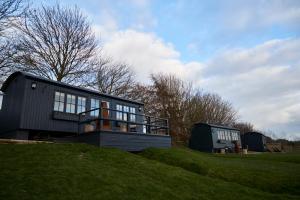 a house on top of a grassy hill at Hog Deer Creek - At Port Lympne Reserve in Hythe