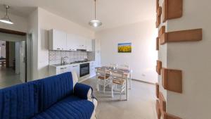 a living room with a blue couch and a kitchen at Due passi dal mare in Montecorice