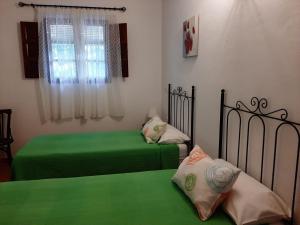 - 2 lits dans une chambre avec des draps verts dans l'établissement VILLA AURORA, à Gaucín