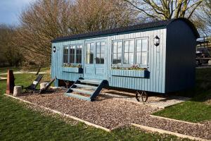 a blue tiny house sitting in a yard at Hog Deer Creek - At Port Lympne Hotel & Reserve in Hythe
