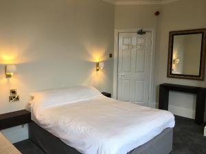 1 dormitorio con cama blanca y chimenea en Coniston Guest House, en Sheffield