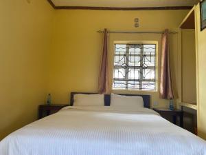 a bedroom with a large white bed and a window at Ranges View Lodge Staycation in Kiamuturi
