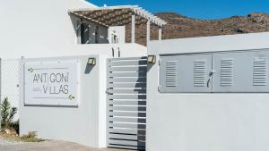 a white fence with an art corn villas sign on it at Antigoni Villas in Gavrio