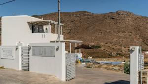 a white building with a mountain in the background at Antigoni Villas in Gavrio
